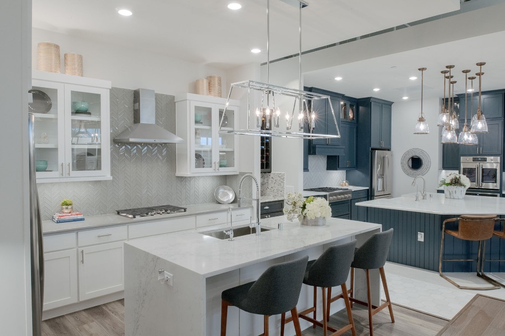 Spacious modern kitchen with marble island, white and navy cabinetry, and stainless appliances